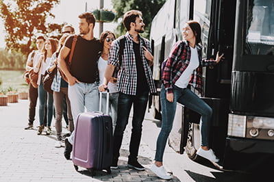 Passengers step aboard a charter bus rental with their luggage